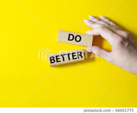 Do better symbol. Wooden blocks with words Do better. Beautiful yellow background. Businessman hand. Business and Do better concept. Copy space. 98001775