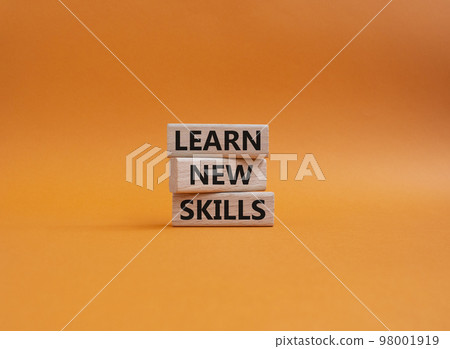 Learn new skills symbol. Concept words 'Learn new skills' on wooden blocks. Beautiful orange background. Business and Learn new skills concept. Copy space. 98001919