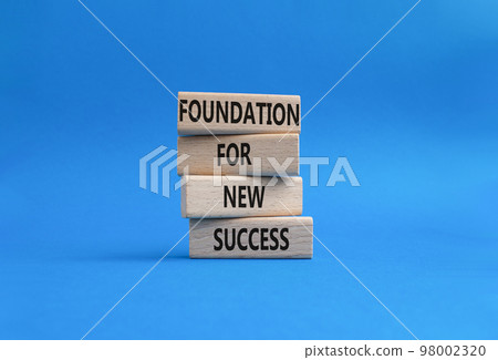 Foundation for new success symbol. Wooden blocks with words Foundation for new success. Beautiful blue background. Business and Foundation for new success concept. Copy space. 98002320