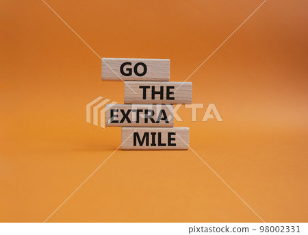 Go the extra mile symbol. Wooden blocks with words Go the extra mile. Beautiful orange background. Business and Go the extra mile concept. Copy space. 98002331