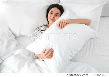 Young woman with pillow in bed, top view. Lazy morning Young woman with pillow in bed, top view. Lazy morning 98002382