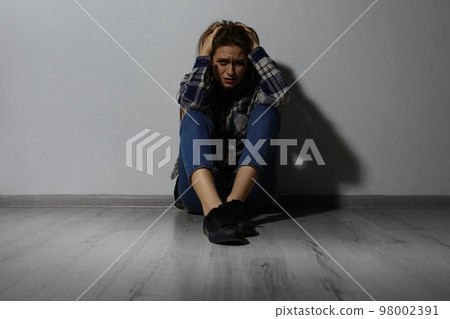 Abused young woman crying near white wall. Domestic violence concept 98002391