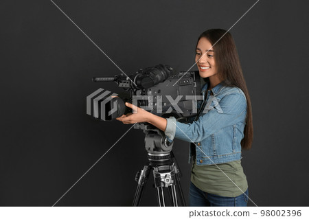 Operator with professional video camera on black background 98002396