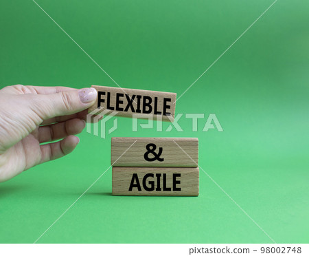 Flexible and agile symbol. Concept word Flexible and agile on wooden blocks. Beautiful green background. Businessman hand. Business and Flexible and agile concept. Copy space. 98002748
