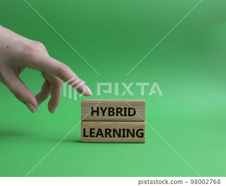 Hybrid learning symbol. Concept word Hybrid learning on wooden blocks. Beautiful green background. Businessman hand. Business and Hybrid learning concept. Copy space Hybrid learning symbol. Concept word Hybrid learning on wooden blocks. Beautiful green background. Businessman hand. Business and Hybrid learning concept. Copy space 98002768