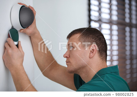 Technician installing CCTV camera on wall indoors 98002825