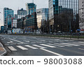 Pedestrian crossing across a wide street against the background of office buildings. 98003088