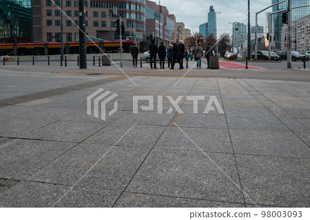 The sidewalk is paved with granite tiles against the background of a pedestrian crossing. 98003093