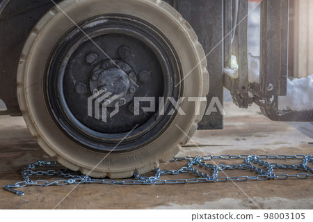 The process of installing an anti-skid chain on a wheel in winter. Preparing a loader, tractor or truck for a snowy road. Snow chains close up The process of installing an anti-skid chain on a wheel in winter. Preparing a loader, tractor or truck for a snowy road. Snow chains close up 98003105