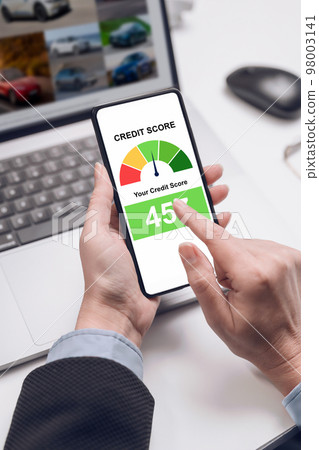 A woman holding a smartphone shows a credit score app on the screen. bank credit report. 98003141