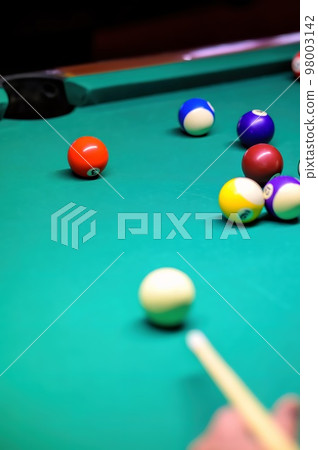 Playing billiards on a green table. A close-up of a billiard ball that the player is aiming at. 98003142