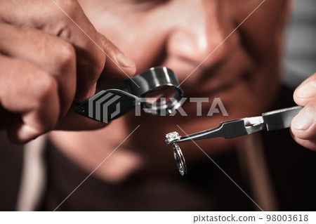 Professional jeweler evaluating beautiful ring, closeup view Professional jeweler evaluating beautiful ring, closeup view 98003618