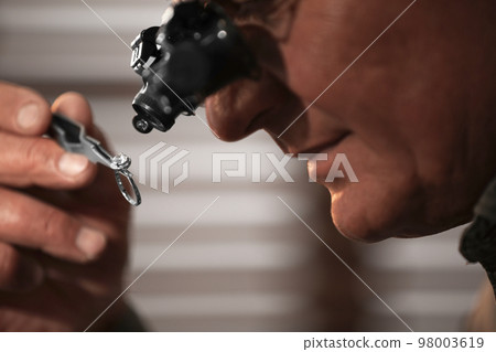 Professional jeweler working with beautiful ring indoors, closeup 98003619