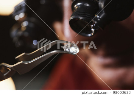 Professional jeweler evaluating beautiful gemstone, closeup view 98003623