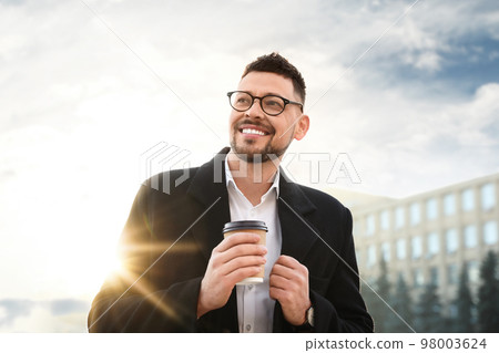 Man with cup of coffee on city street in morning 98003624