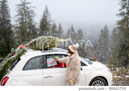 Woman travels by car with presents and Christmas tree on the mountain road Woman travels by car with presents and Christmas tree on the mountain road 98003750