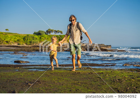 Father and son tourists on the background of Tanah Lot - Temple in the Ocean. Bali, Indonesia. Traveling with children concept 98004092