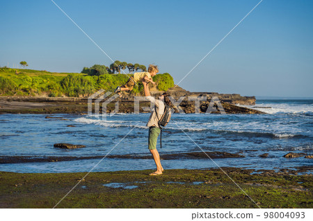Father and son tourists on the background of Tanah Lot - Temple in the Ocean. Bali, Indonesia. Traveling with children concept 98004093