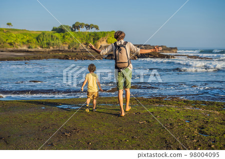 Father and son tourists on the background of Tanah Lot - Temple in the Ocean. Bali, Indonesia. Traveling with children concept Father and son tourists on the background of Tanah Lot - Temple in the Ocean. Bali, Indonesia. Traveling with children concept 98004095
