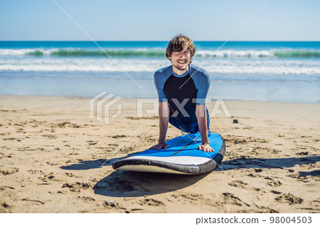 Young man surfer training before go to lineup on a sand beach. Learning to surf. Vacation concept. Summer holidays. Tourism, sport Young man surfer training before go to lineup on a sand beach. Learning to surf. Vacation concept. Summer holidays. Tourism, sport 98004503