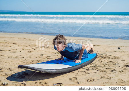 Young man surfer training before go to lineup on a sand beach. Learning to surf. Vacation concept. Summer holidays. Tourism, sport Young man surfer training before go to lineup on a sand beach. Learning to surf. Vacation concept. Summer holidays. Tourism, sport 98004508