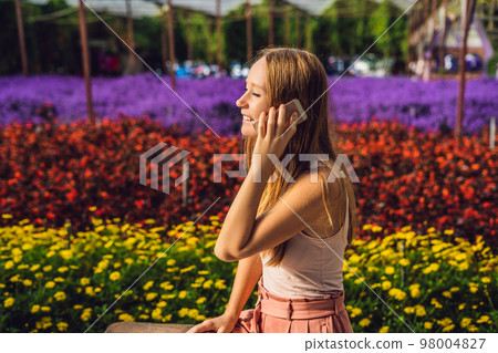 Young woman in a flower greenhouse. Bright tropical flowers. 98004827