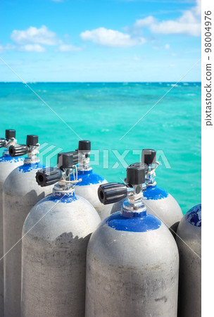 Close up picture of scuba tanks with turquoise water in the background, selective focus. 98004976