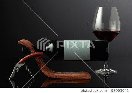 Red wine and corkscrew on a black reflective background. Red wine and corkscrew on a black reflective background. 98005041