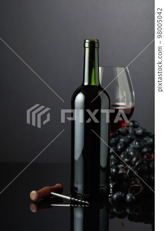 Red wine and blue grapes on a black background. 98005042