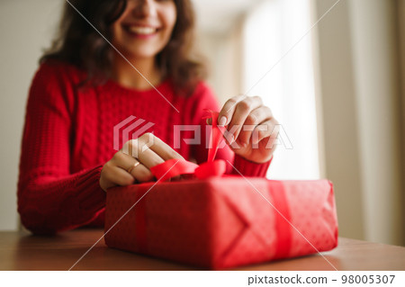 Female hands opening red gift box. Unpacking a gift. Valentines day celebration concept. Female hands opening red gift box. Unpacking a gift. Valentines day celebration concept. 98005307