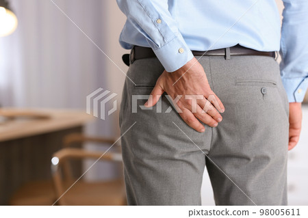 Man suffering from hemorrhoid in office, closeup 98005611