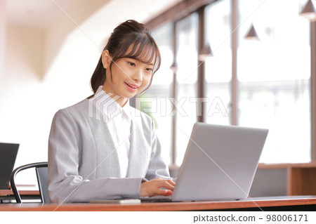 A woman who smiles at her desk at the office_Gray jacket 1 98006171