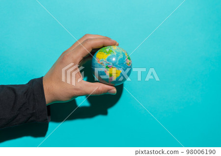 Hand holding globe ball in colorful blue background with copy space for text. Hand holding globe ball in colorful blue background with copy space for text. 98006190