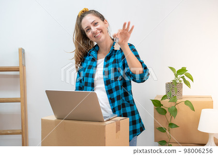 Portrait of happy young attractive woman with laptop on cardboard boxes moving in a new home. Portrait of happy young attractive woman with laptop on cardboard boxes moving in a new home. 98006256