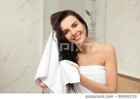 Young woman drying hair with towel in bathroom 98006339