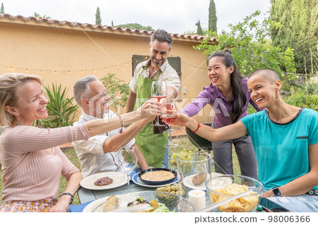 Happy friends toasting with big smile around the table at house patio diner. Happy friends toasting with big smile around the table at house patio diner. 98006366