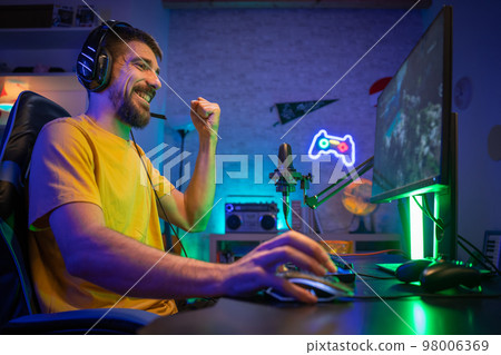 Professional Gamer winning and celebrating victory Online Video Game on Computer side view Professional Gamer winning and celebrating victory Online Video Game on Computer side view 98006369