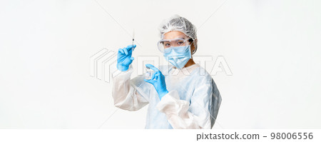 Asian doctor or nurse in medical protective equipment, looking confident at camera, holding syringe and vaccine from covid-19, vaccination campaign and medical concept Asian doctor or nurse in medical protective equipment, looking confident at camera, holding syringe and vaccine from covid-19, vaccination campaign and medical concept 98006556