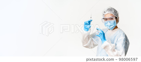 Asian doctor or nurse in medical protective equipment, looking confident at camera, holding syringe and vaccine from covid-19, vaccination campaign and medical concept Asian doctor or nurse in medical protective equipment, looking confident at camera, holding syringe and vaccine from covid-19, vaccination campaign and medical concept 98006597