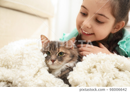 Cute little girl with cat lying at home. First pet 98006642