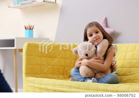 Cute little girl sitting on sofa at home Cute little girl sitting on sofa at home 98006702