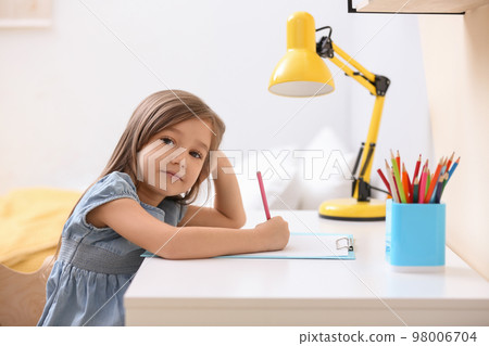 Cute little girl drawing at table in room 98006704