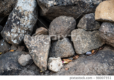 Closeup of large rocks or boulders near the mountains. Large multicolored granites. Details of big grey stone structures with orange particles shining in the sunlight. Closeup of large rocks or boulders near the mountains. Large multicolored granites. Details of big grey stone structures with orange particles shining in the sunlight. 98007351