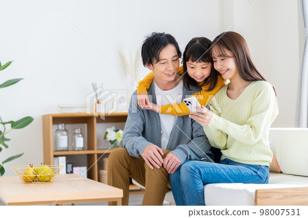 A young family looking at a smartphone in the living room 98007531