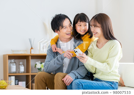 一個年輕的家庭在客廳裡看智能手機 一個年輕的家庭在客廳裡看智能手機 98007533