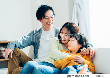 A young family relaxing in the living room　 98007600
