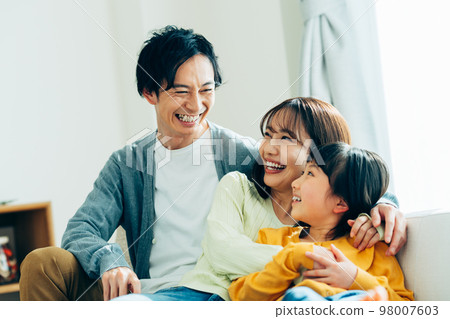 A young family relaxing in the living room　 98007603