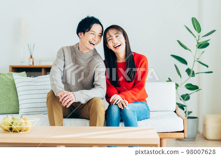 Young couple relaxing in the living room Young couple relaxing in the living room 98007628