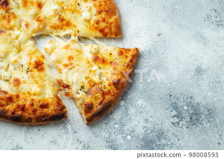 Italian pizza four cheeses with stretching cheese and basil on a light concrete background. 98008593