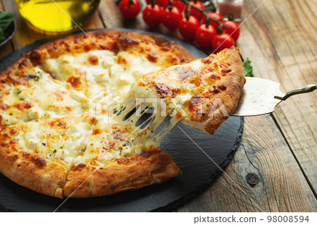 A slice of hot Italian pizza with stretching cheese. Pizza four cheeses with basil. 98008594